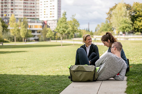 Drei Personen sitzen im Park